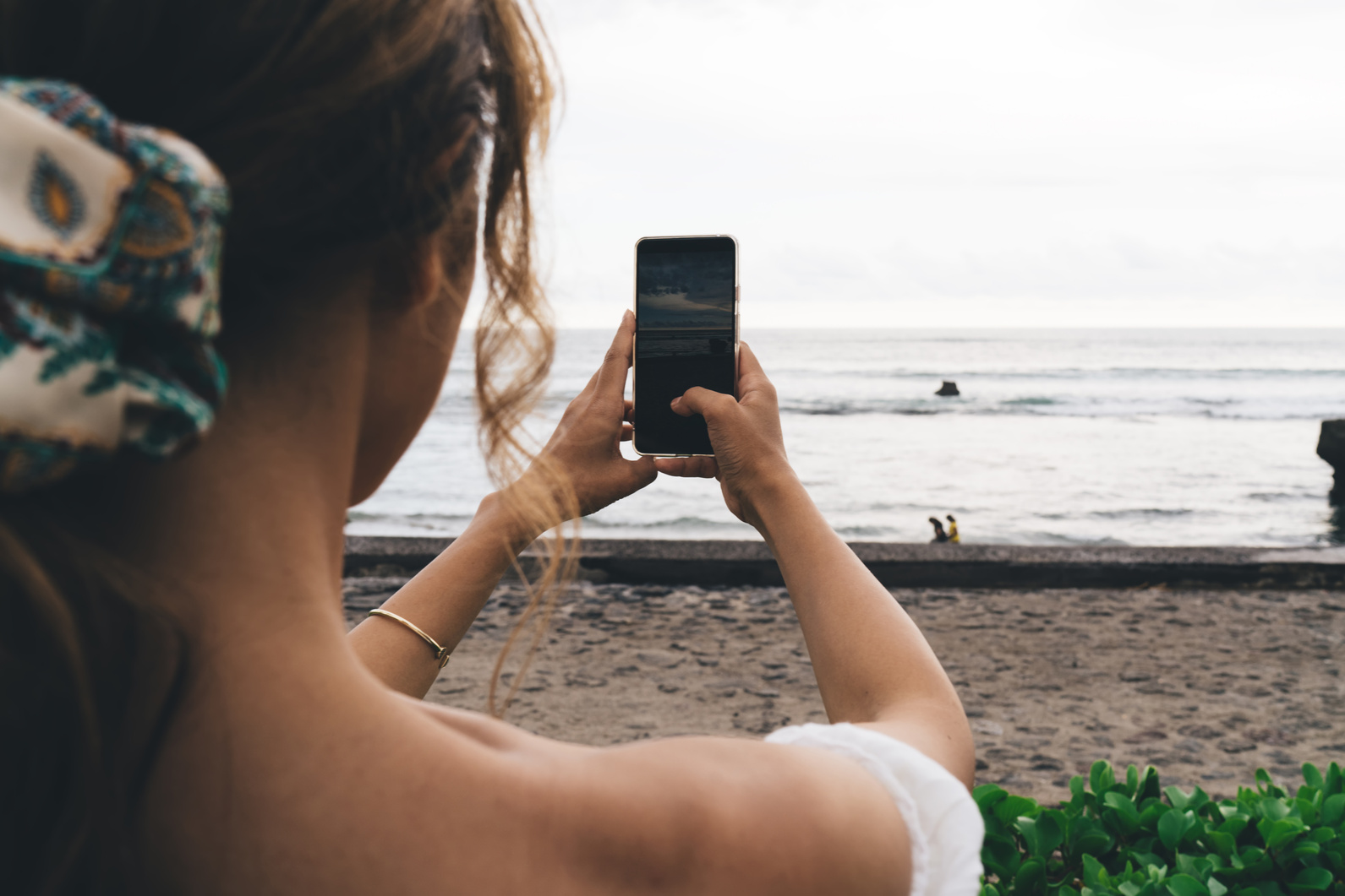 Faceless woman taking photo of sea